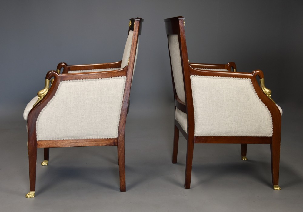 A pair of early 20th-century French Empire style mahogany armchairs featuring light neutral upholstery and gilt bronze mounts. View IX