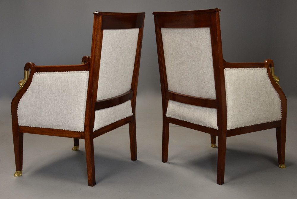 A pair of early 20th-century French Empire style mahogany armchairs featuring light neutral upholstery and gilt bronze mounts. View XII