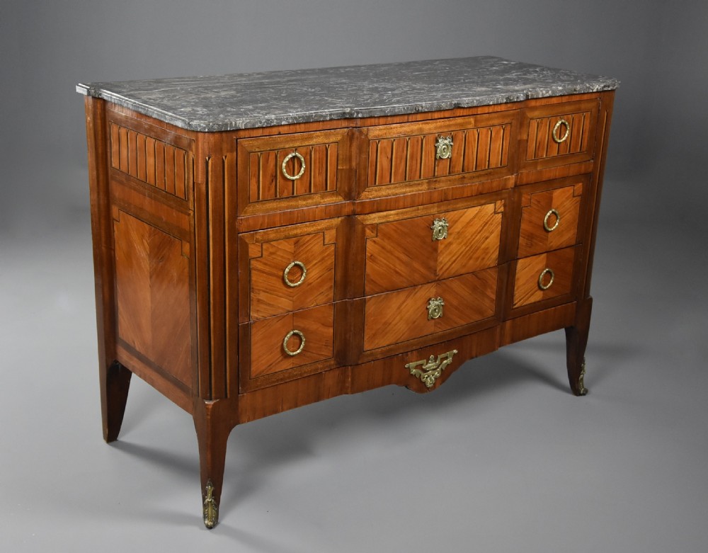 A late nineteenth-century French Louis XVI style tulipwood breakfront commode featuring inlaid parquetry panels, ring-pull brass handles, and a fitted grey marble top. View II