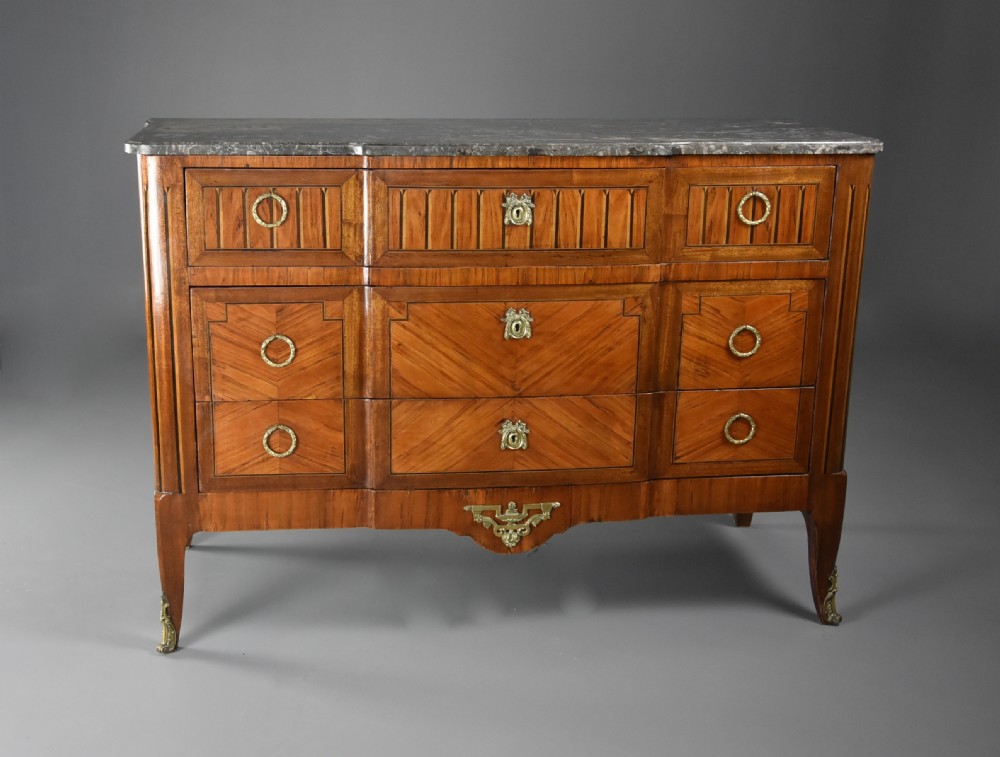 A late nineteenth-century French Louis XVI style tulipwood breakfront commode featuring inlaid parquetry panels, ring-pull brass handles, and a fitted grey marble top. View IV
