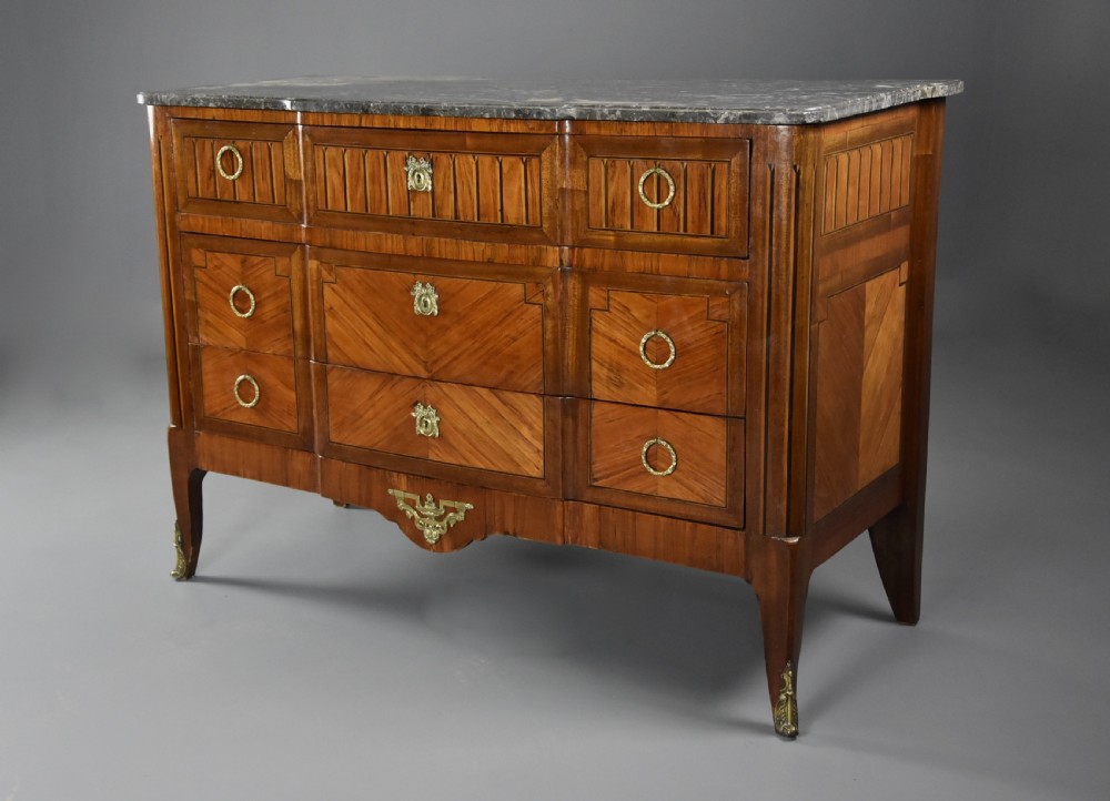 A late nineteenth-century French Louis XVI style tulipwood breakfront commode featuring inlaid parquetry panels, ring-pull brass handles, and a fitted grey marble top. View VI
