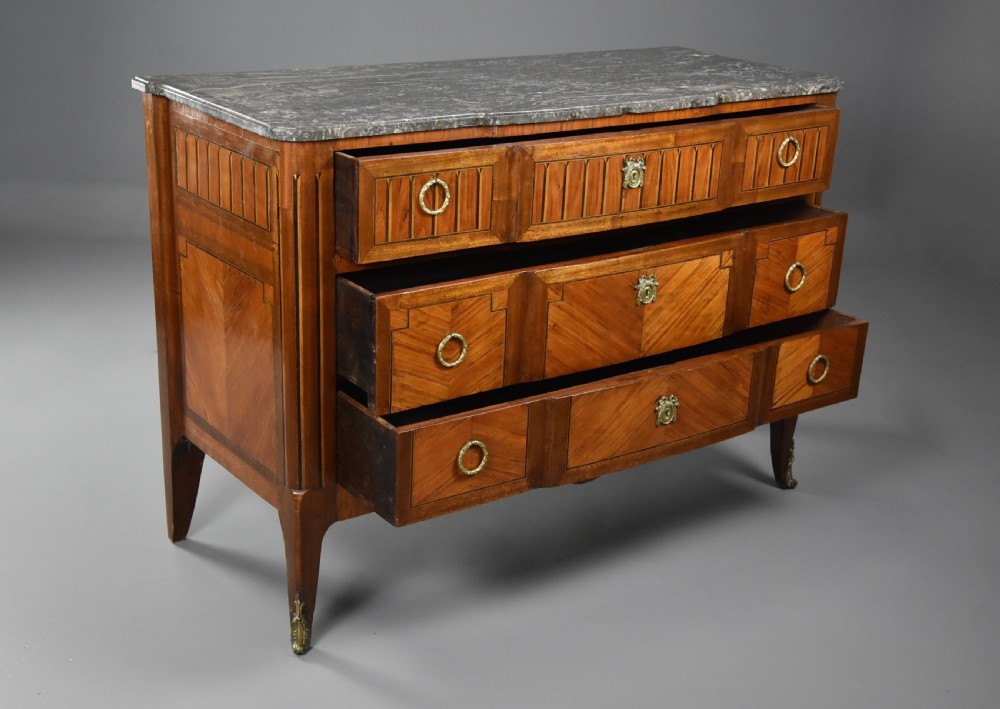 A late nineteenth-century French Louis XVI style tulipwood breakfront commode featuring inlaid parquetry panels, ring-pull brass handles, and a fitted grey marble top. View X