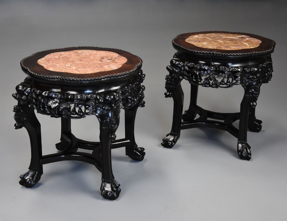 A pair of late nineteenth-century dark hardwood Chinese pot stands featuring carved foliage aprons, cabriole legs, and inset circular pink marble tops. View III