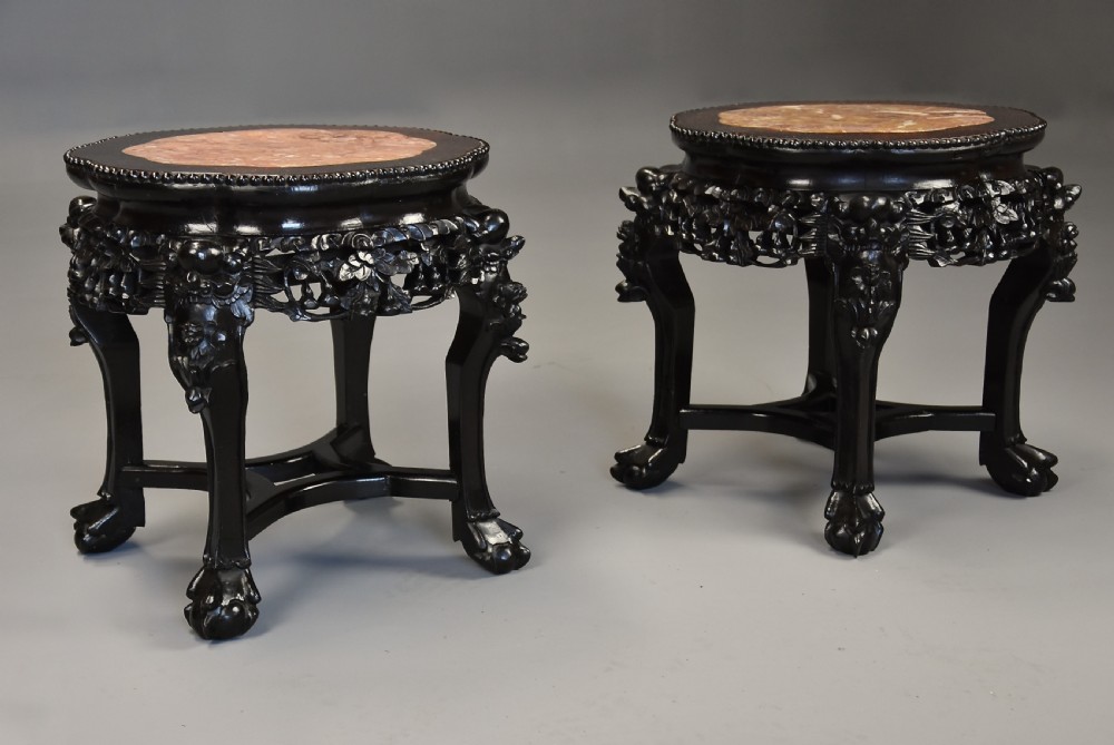 A pair of late nineteenth-century dark hardwood Chinese pot stands featuring carved foliage aprons, cabriole legs, and inset circular pink marble tops. View IV