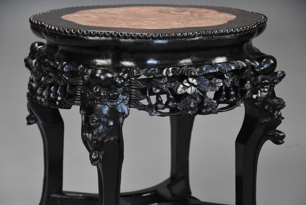 A pair of late nineteenth-century dark hardwood Chinese pot stands featuring carved foliage aprons, cabriole legs, and inset circular pink marble tops. View VI