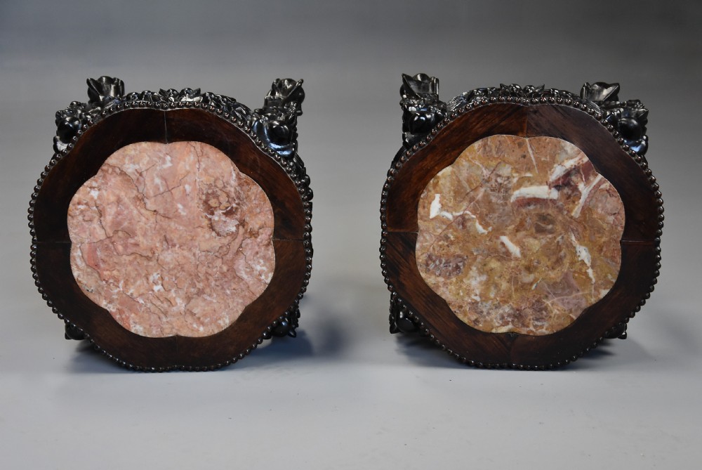 A pair of late nineteenth-century dark hardwood Chinese pot stands featuring carved foliage aprons, cabriole legs, and inset circular pink marble tops. View VIII