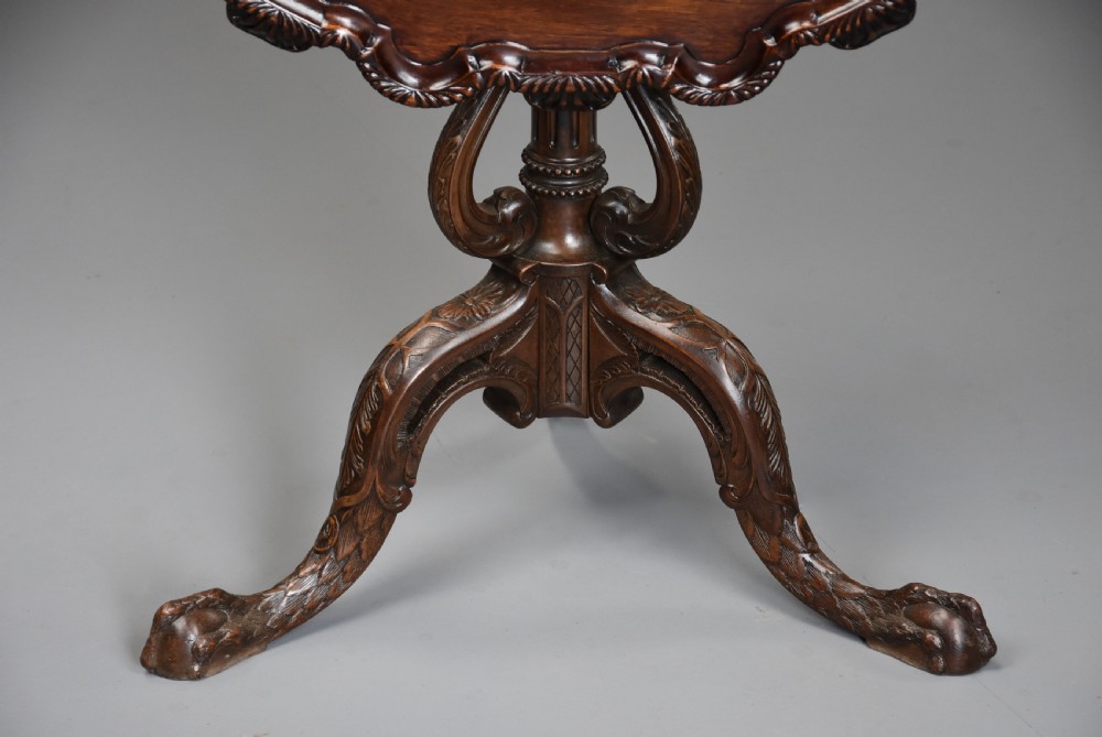 An early twentieth-century mahogany tilt-top tripod table with a carved piecrust border, turned column, and cabriole legs ending in claw-and-ball feet. View XI