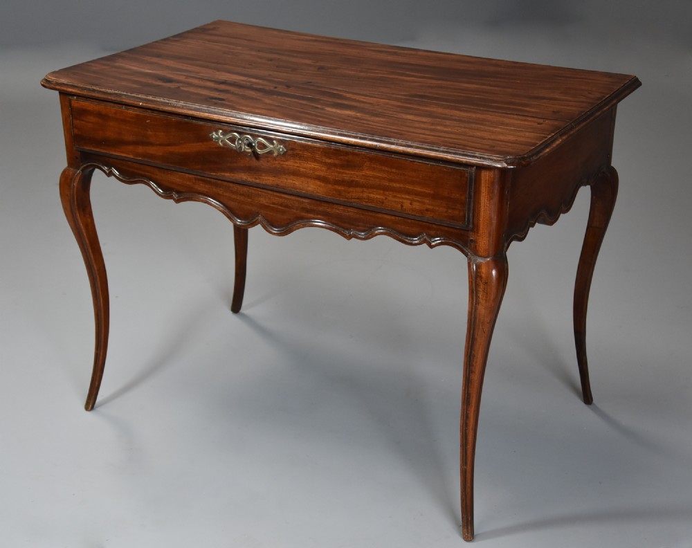 A late 18th-century French walnut side table featuring slender cabriole legs, a scalloped apron, and a single frieze drawer with a brass keyhole escutcheon.