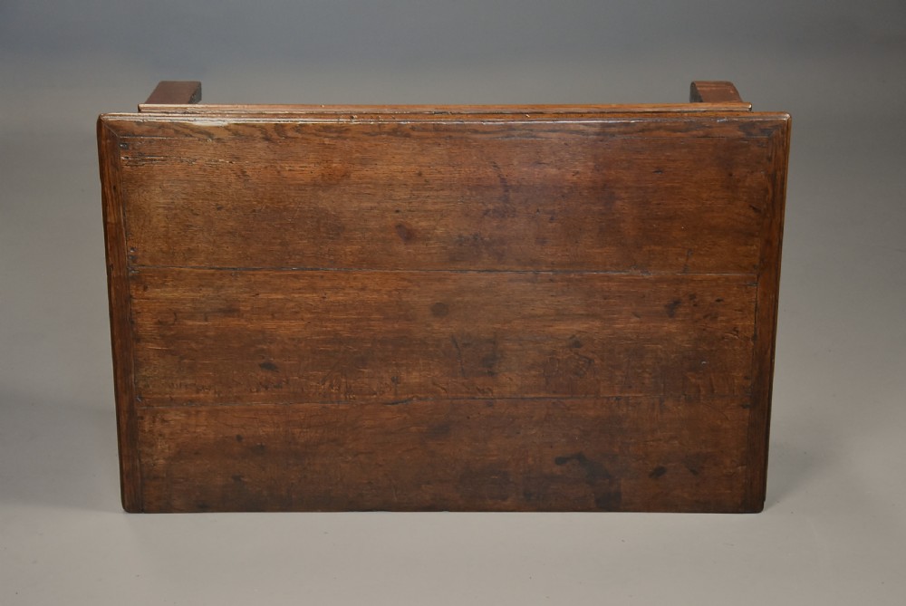 A late 17th-century oak chest of drawers featuring geometric moulded drawer fronts, brass drop handles, and decorative brass escutcheons. View X