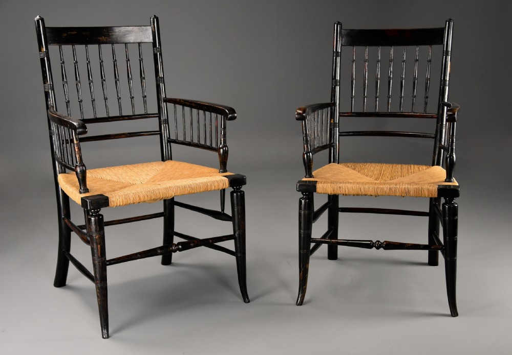 A pair of late nineteenth-century ebonised wooden armchairs featuring turned spindle backrests, woven rush seats, and turned legs with stretchers. View II
