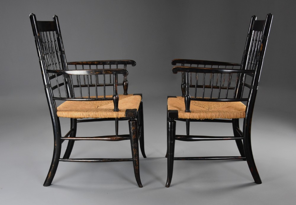 A pair of late nineteenth-century ebonised wooden armchairs featuring turned spindle backrests, woven rush seats, and turned legs with stretchers. View V