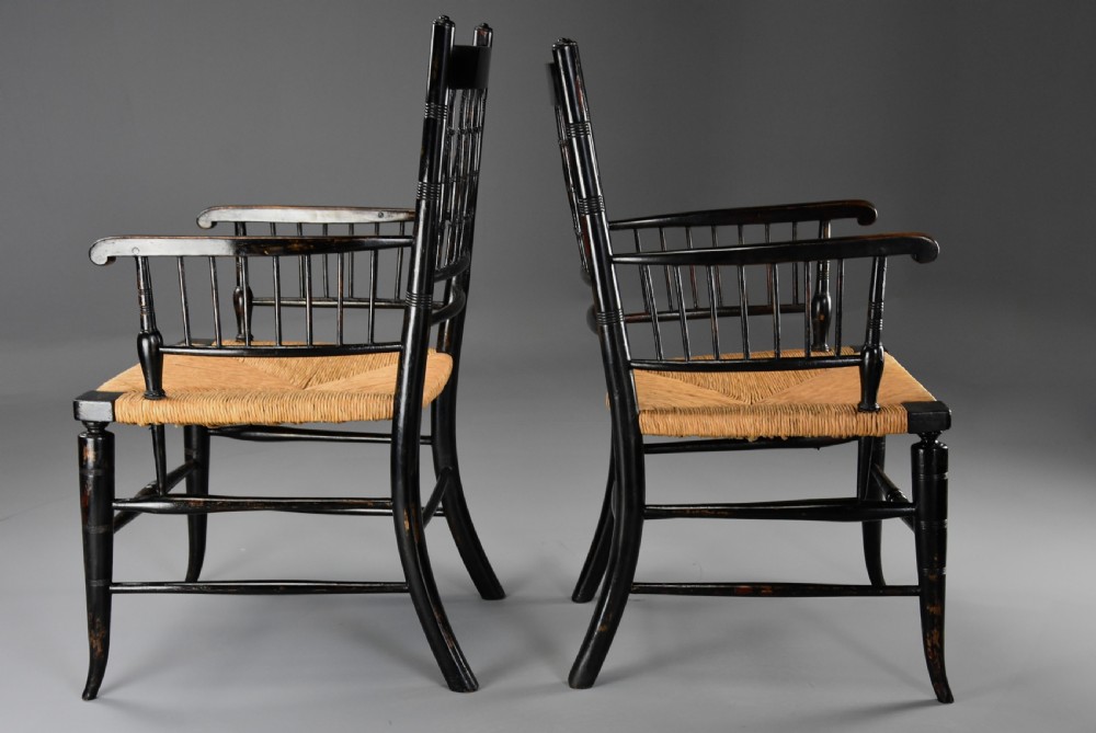 A pair of late nineteenth-century ebonised wooden armchairs featuring turned spindle backrests, woven rush seats, and turned legs with stretchers. View VI