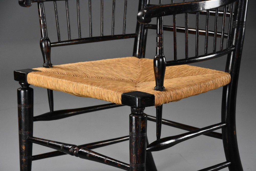 A pair of late nineteenth-century ebonised wooden armchairs featuring turned spindle backrests, woven rush seats, and turned legs with stretchers. View XII