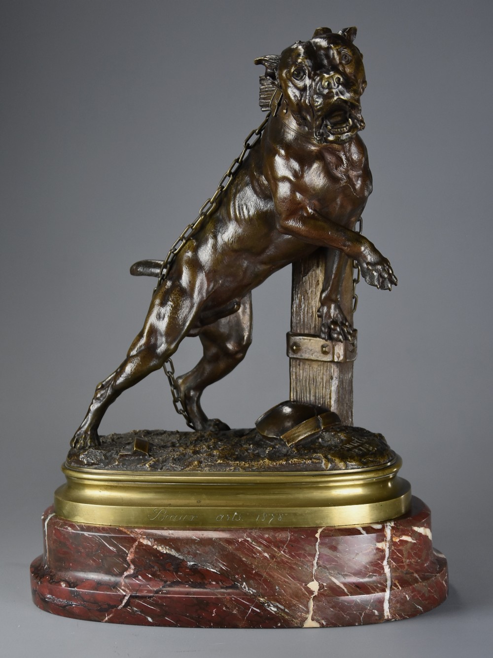 A 19th-century dark bronze sculpture of a chained guard dog rearing against a post, mounted on a brass collar and red veined marble base.