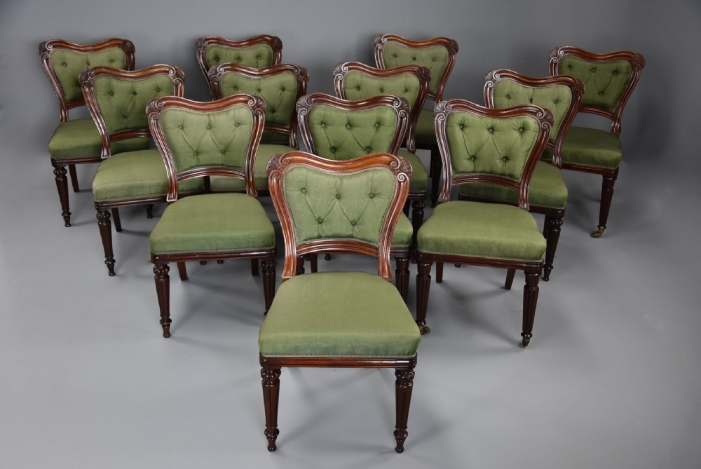 A matched set of twelve mid-19th century William IV mahogany dining chairs featuring buttoned green upholstered backrests and turned fluted front legs on brass castors. View III