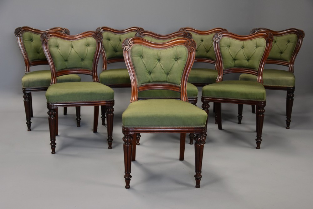 A matched set of twelve mid-19th century William IV mahogany dining chairs featuring buttoned green upholstered backrests and turned fluted front legs on brass castors. View V