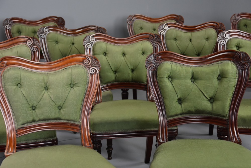 A matched set of twelve mid-19th century William IV mahogany dining chairs featuring buttoned green upholstered backrests and turned fluted front legs on brass castors. View VI