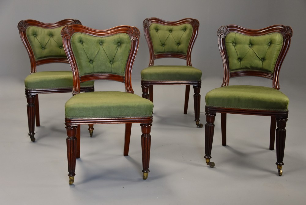 A matched set of twelve mid-19th century William IV mahogany dining chairs featuring buttoned green upholstered backrests and turned fluted front legs on brass castors. View VII