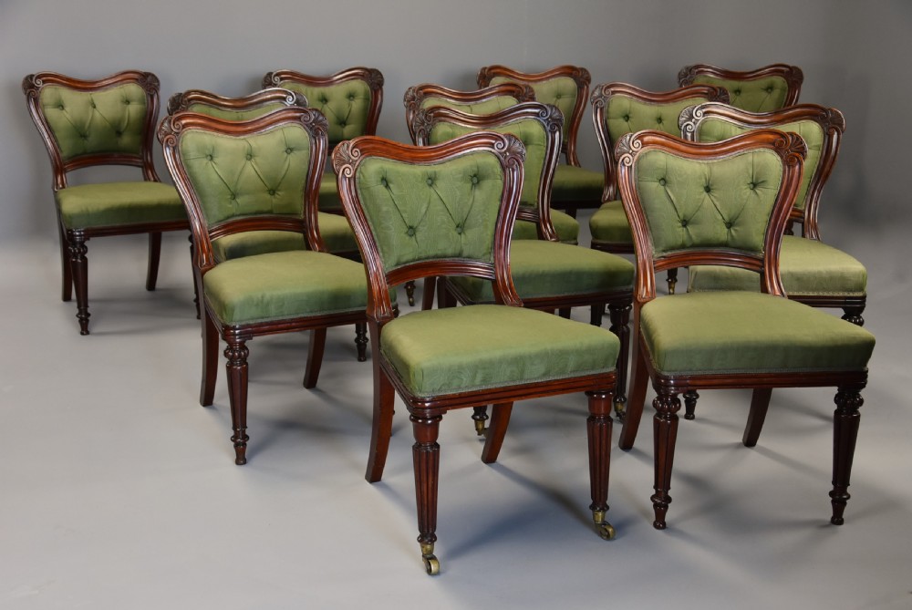 A matched set of twelve mid-19th century William IV mahogany dining chairs featuring buttoned green upholstered backrests and turned fluted front legs on brass castors. View IX