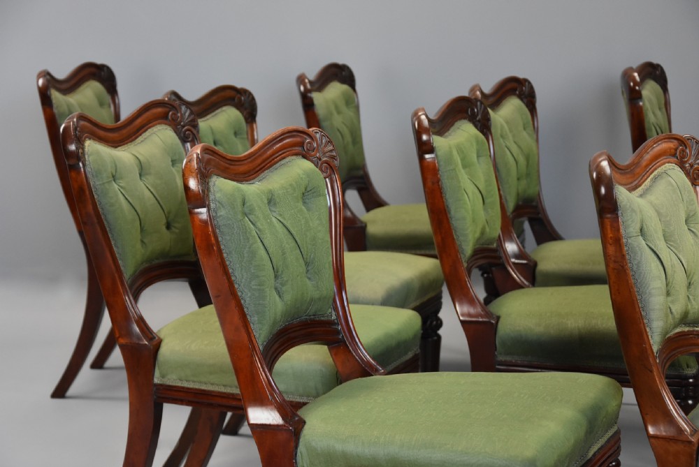 A matched set of twelve mid-19th century William IV mahogany dining chairs featuring buttoned green upholstered backrests and turned fluted front legs on brass castors. View X