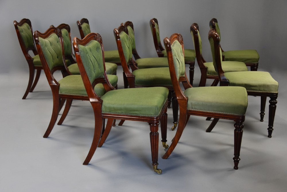 A matched set of twelve mid-19th century William IV mahogany dining chairs featuring buttoned green upholstered backrests and turned fluted front legs on brass castors. View XI