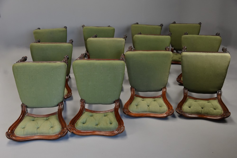 A matched set of twelve mid-19th century William IV mahogany dining chairs featuring buttoned green upholstered backrests and turned fluted front legs on brass castors. View XII