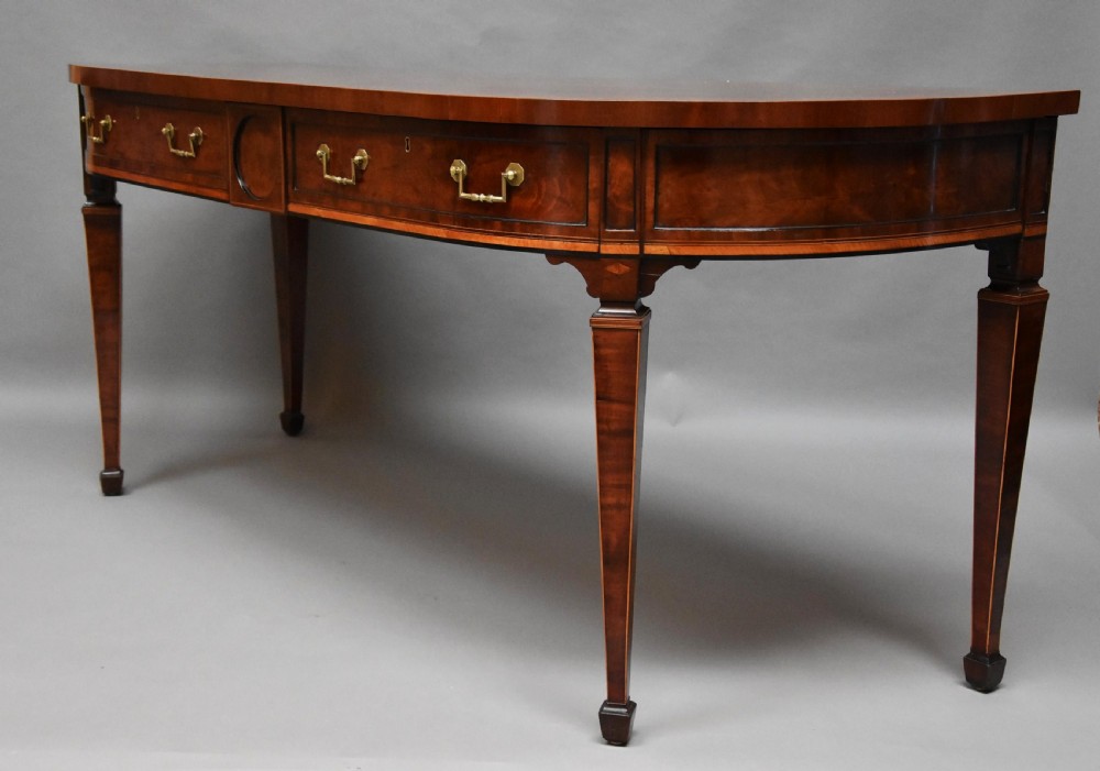 A late 18th-century Sheraton mahogany bowfront side table with two drawers, brass swan-neck handles, boxwood inlay, and square tapered legs. View V