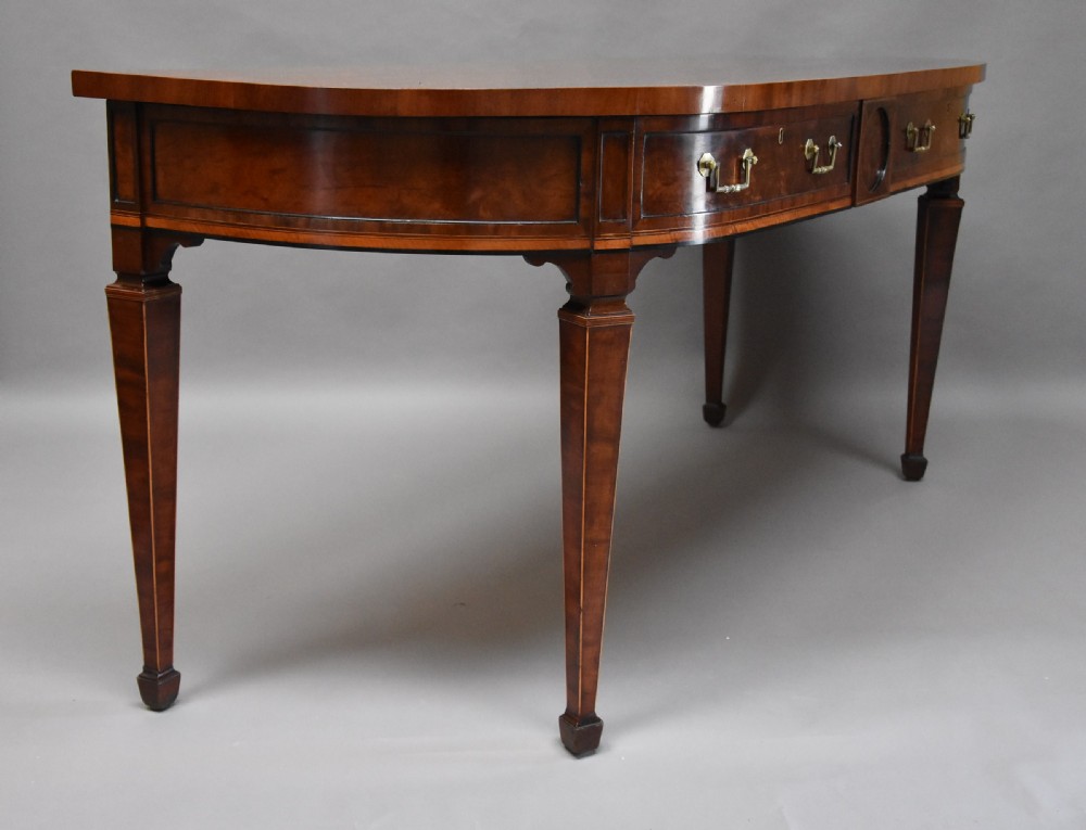 A late 18th-century Sheraton mahogany bowfront side table with two drawers, brass swan-neck handles, boxwood inlay, and square tapered legs. View VIII