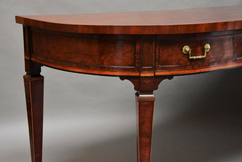 A late 18th-century Sheraton mahogany bowfront side table with two drawers, brass swan-neck handles, boxwood inlay, and square tapered legs. View IX