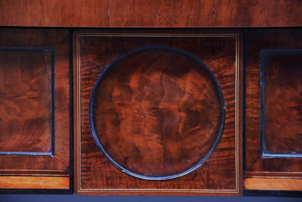 A late 18th-century Sheraton mahogany bowfront side table with two drawers, brass swan-neck handles, boxwood inlay, and square tapered legs. View XII