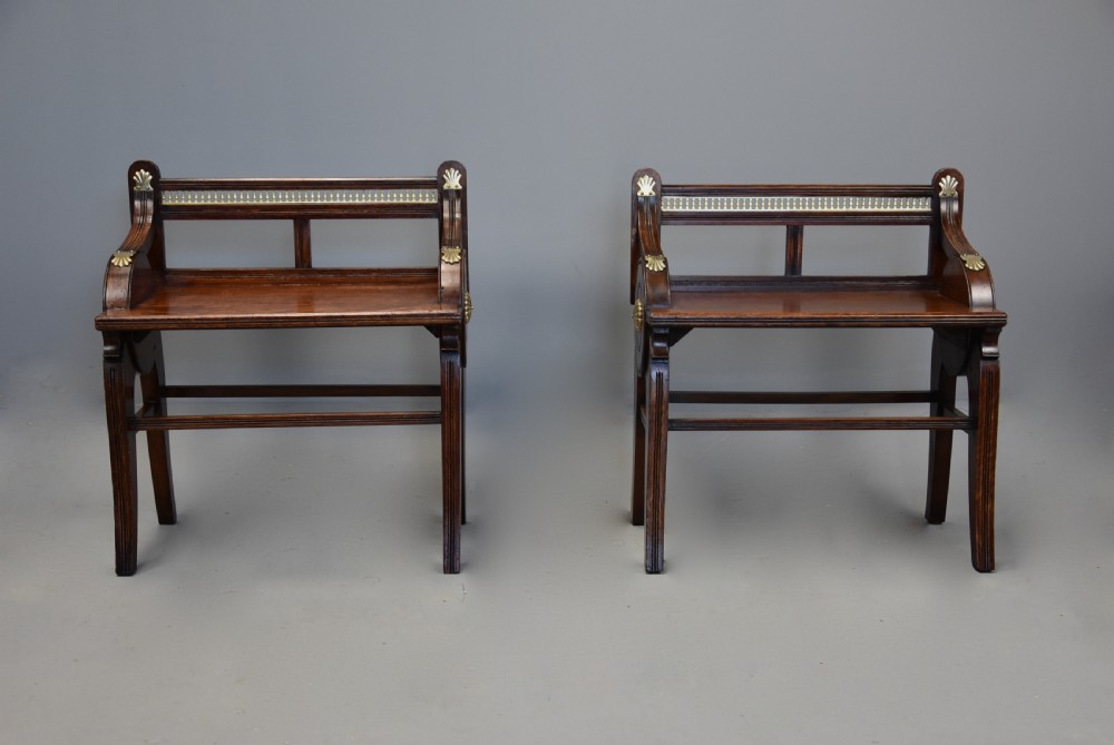A pair of late nineteenth-century dark oak hall benches featuring carved side roundels, brass mounts, and a spindle gallery back. View IV