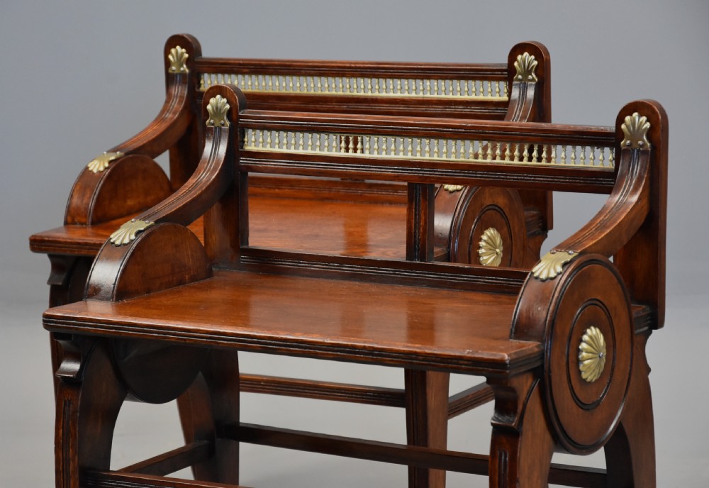 A pair of late nineteenth-century dark oak hall benches featuring carved side roundels, brass mounts, and a spindle gallery back. View VIII