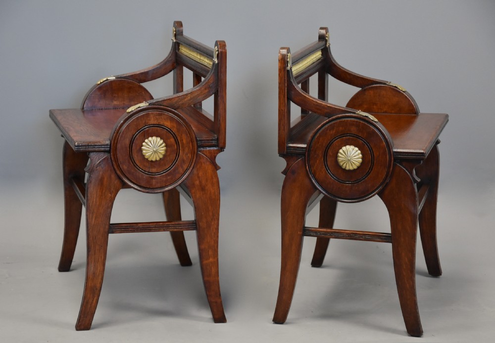 A pair of late nineteenth-century dark oak hall benches featuring carved side roundels, brass mounts, and a spindle gallery back. View IX