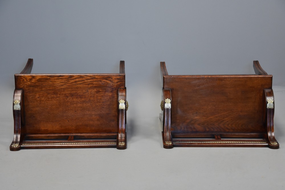 A pair of late nineteenth-century dark oak hall benches featuring carved side roundels, brass mounts, and a spindle gallery back. View X