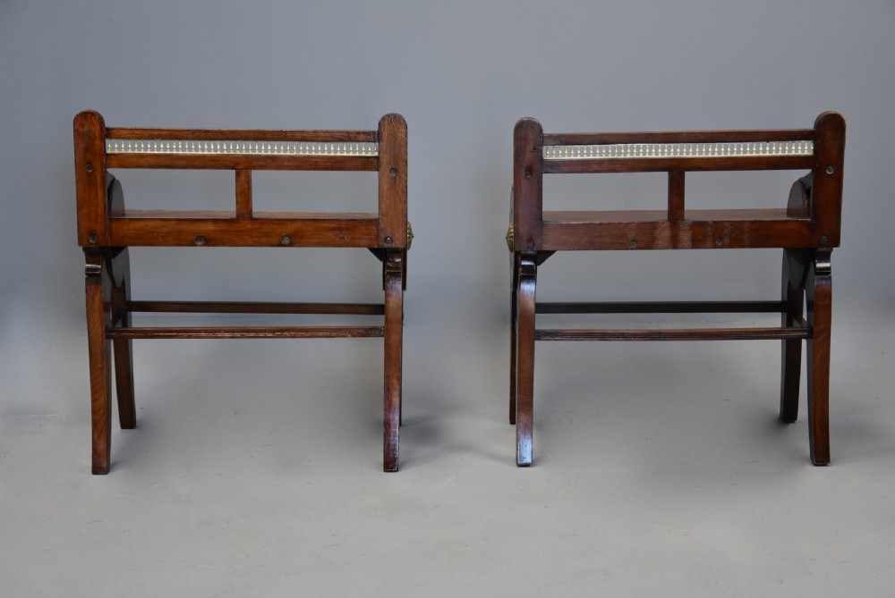 A pair of late nineteenth-century dark oak hall benches featuring carved side roundels, brass mounts, and a spindle gallery back. View XI