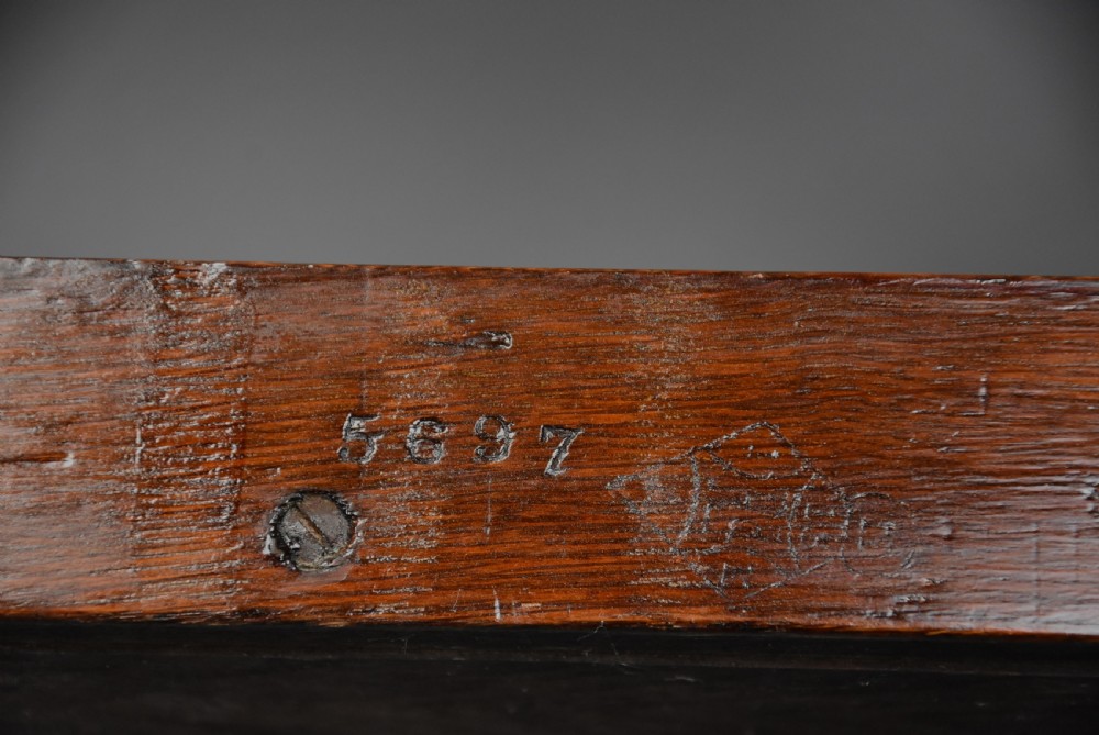 A pair of late nineteenth-century dark oak hall benches featuring carved side roundels, brass mounts, and a spindle gallery back. View XIV