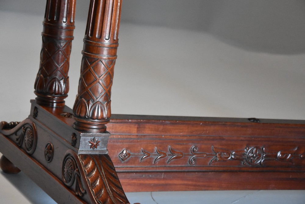 An early 19th-century French Empire mahogany centre table featuring a light marble top, carved frieze, fluted columns, and a trestle base. View X