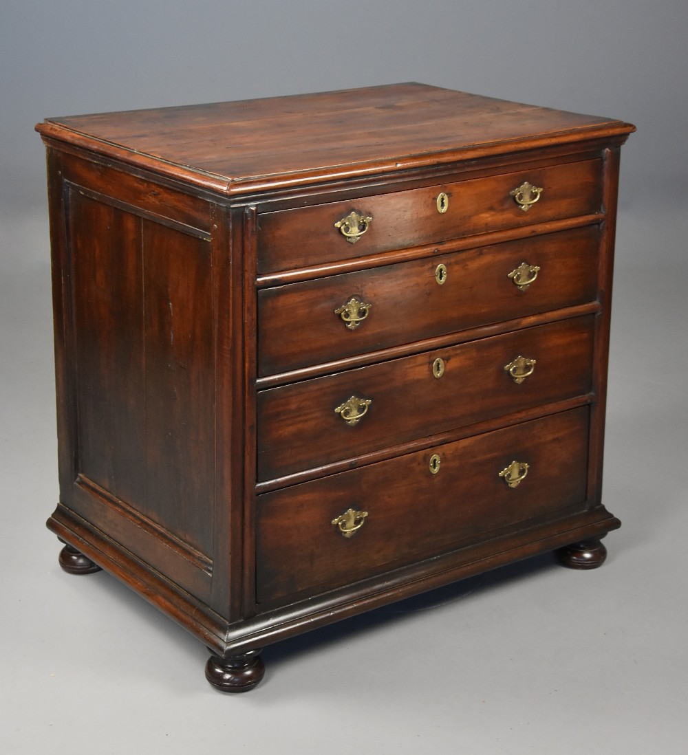A late seventeenth-century fruitwood chest of drawers featuring four graduated drawers with brass drop handles, brass escutcheons, panelled sides, and bun feet.