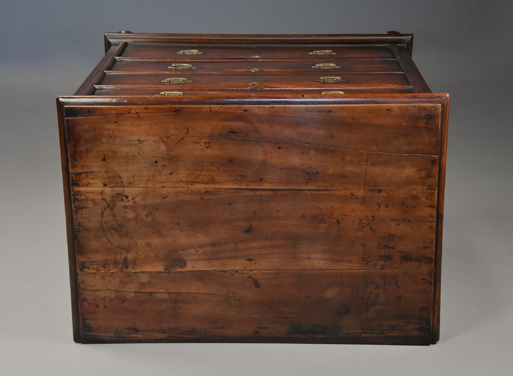 A late seventeenth-century fruitwood chest of drawers featuring four graduated drawers with brass drop handles, brass escutcheons, panelled sides, and bun feet. View X