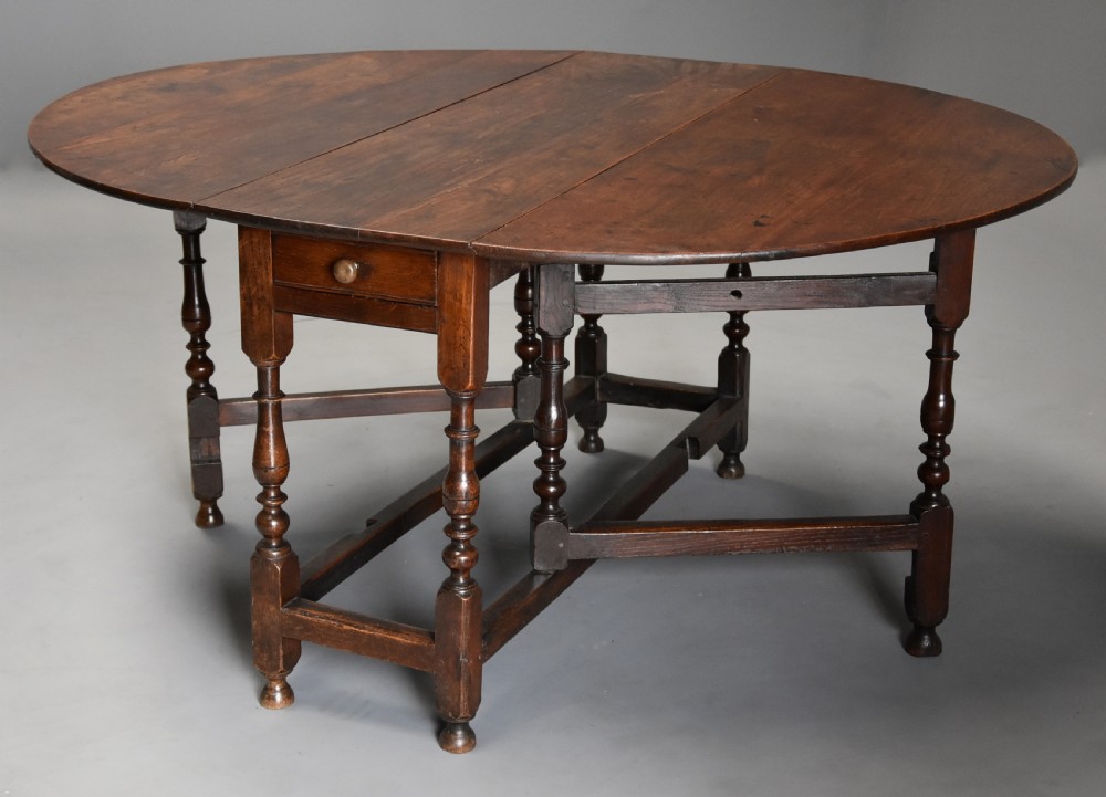 A late 17th-century oak gateleg dining table with an oval drop-leaf top, turned legs, and a small single end drawer. View II