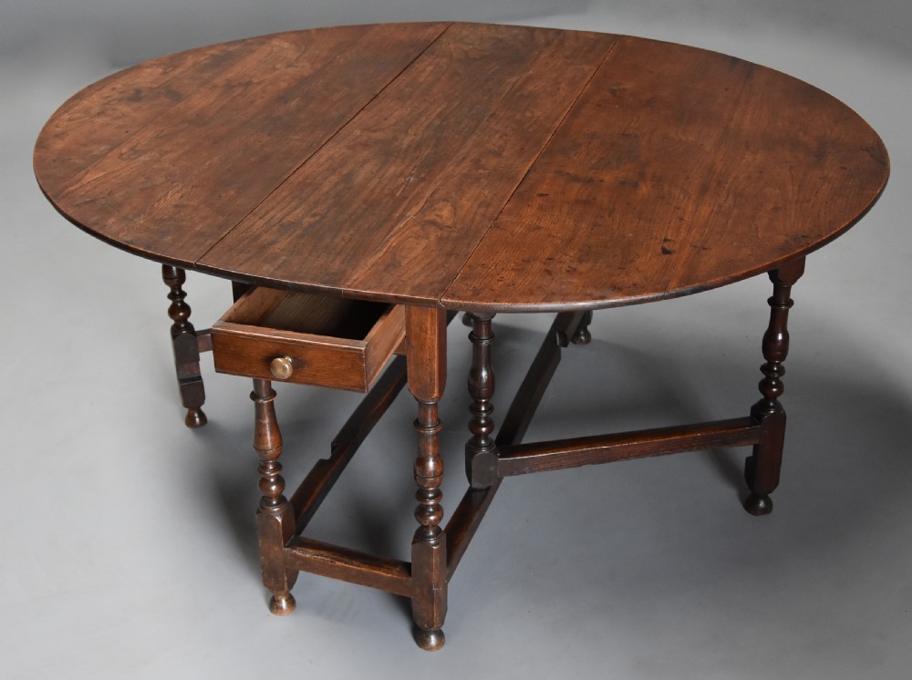 A late 17th-century oak gateleg dining table with an oval drop-leaf top, turned legs, and a small single end drawer. View III