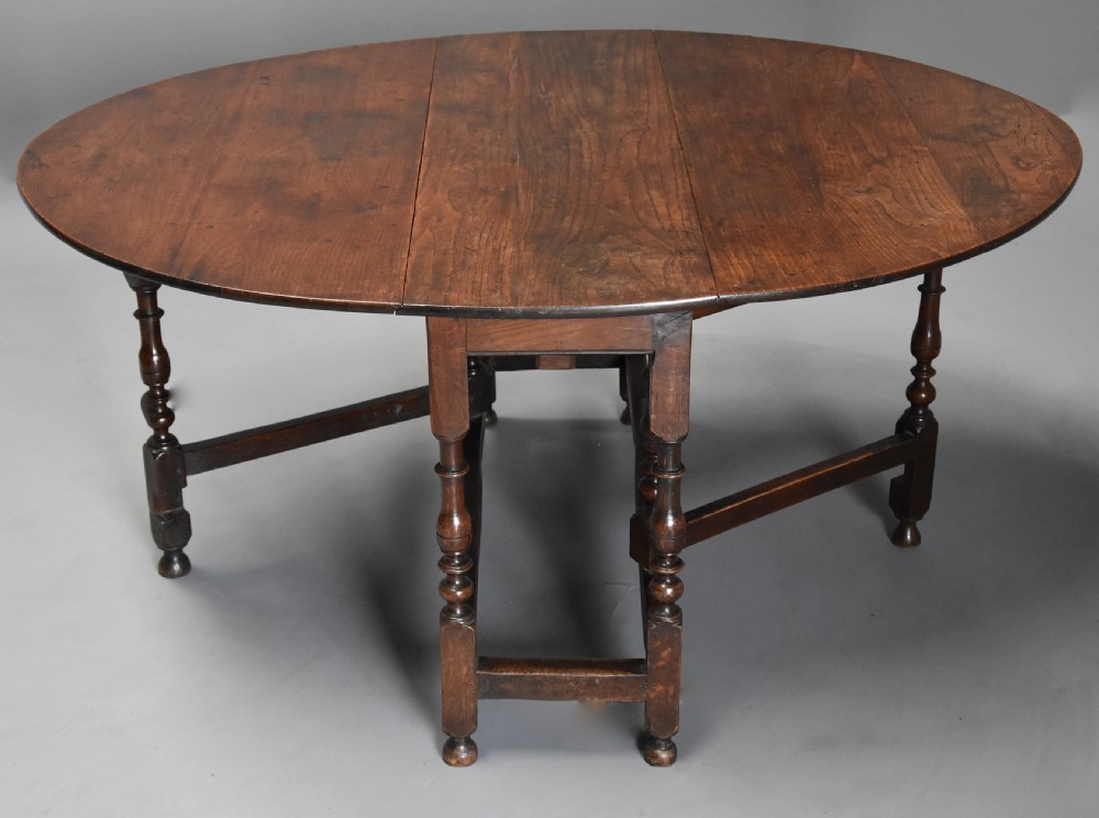 A late 17th-century oak gateleg dining table with an oval drop-leaf top, turned legs, and a small single end drawer. View IV