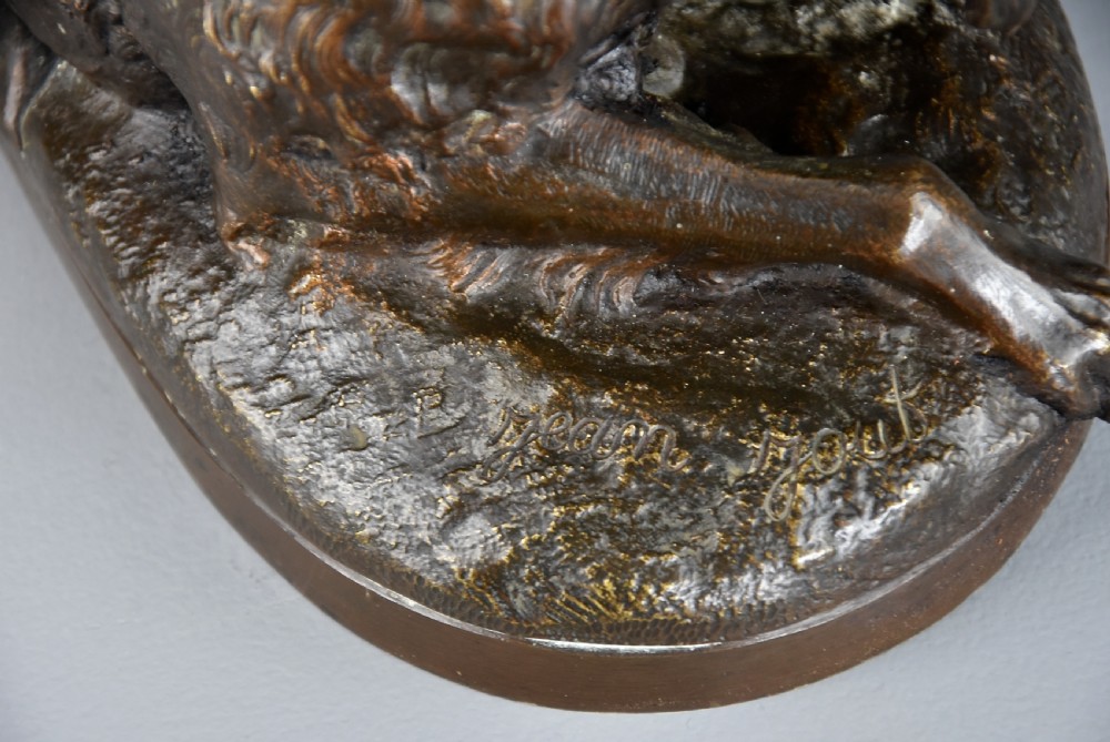 A late 19th-century dark patinated bronze sculpture depicting a winged putto interacting with a recumbent spaniel dog on an oval base. View XII
