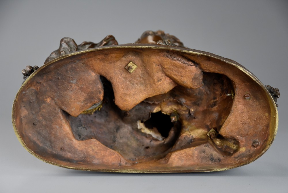 A late 19th-century dark patinated bronze sculpture depicting a winged putto interacting with a recumbent spaniel dog on an oval base. View XIII