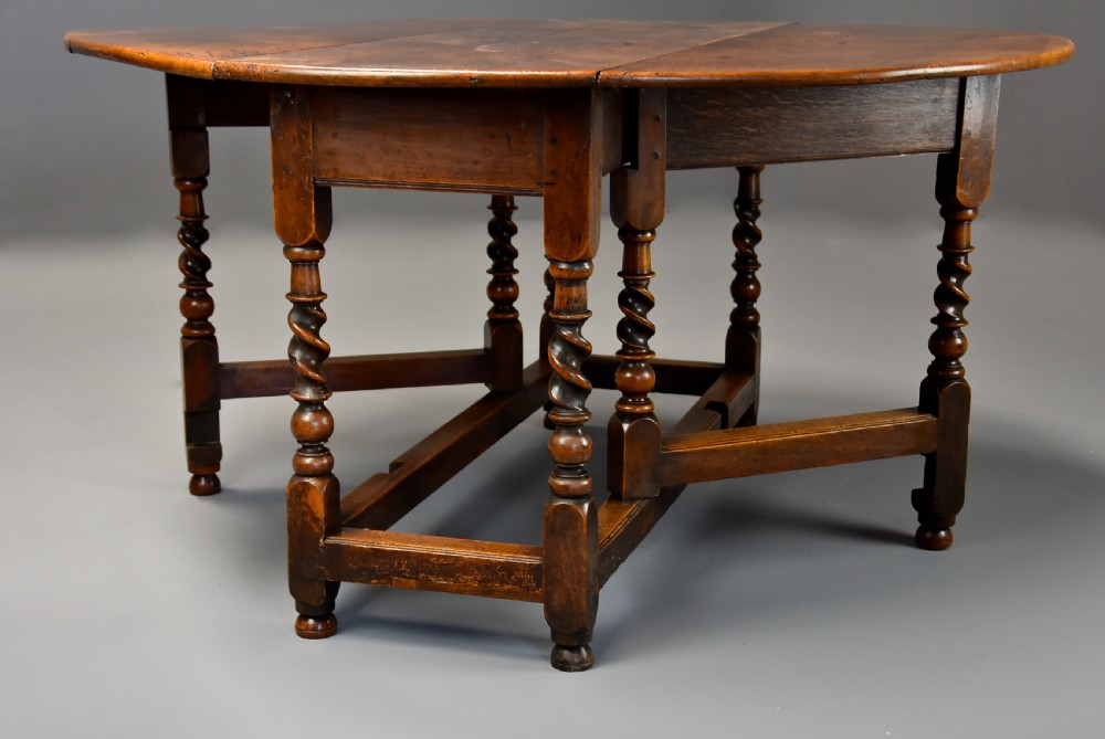 A 17th-century walnut gateleg table with extended oval drop leaves and double barley twist turned legs supported by stretchers. View II