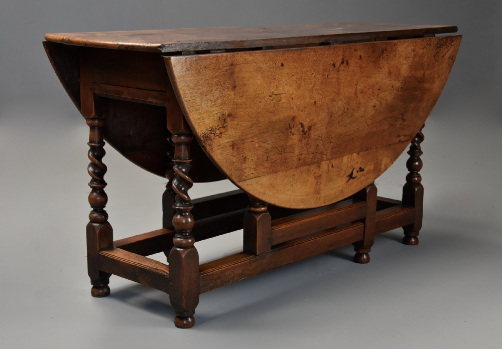 A 17th-century walnut gateleg table with extended oval drop leaves and double barley twist turned legs supported by stretchers. View III