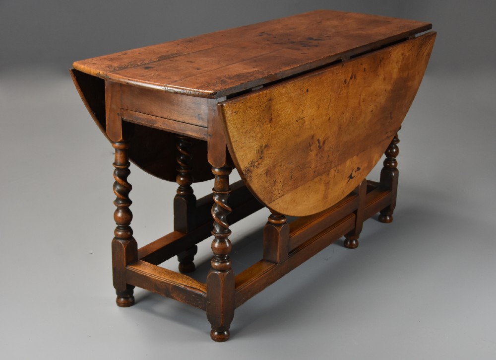 A 17th-century walnut gateleg table with extended oval drop leaves and double barley twist turned legs supported by stretchers. View IV