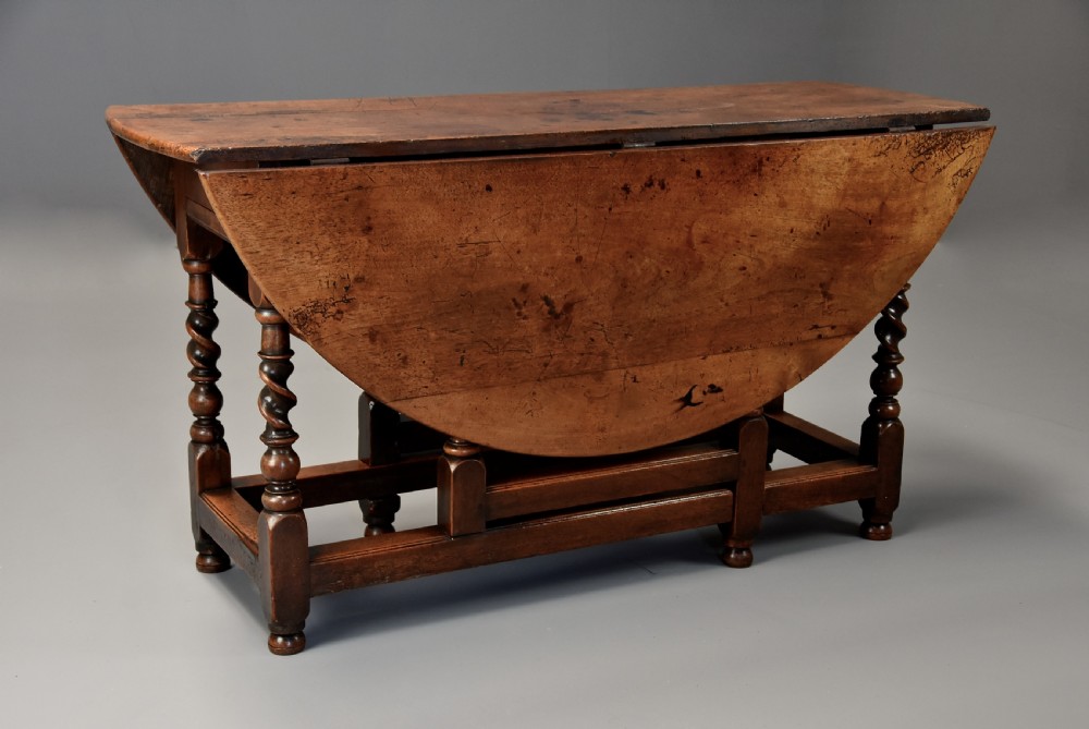 A 17th-century walnut gateleg table with extended oval drop leaves and double barley twist turned legs supported by stretchers. View V