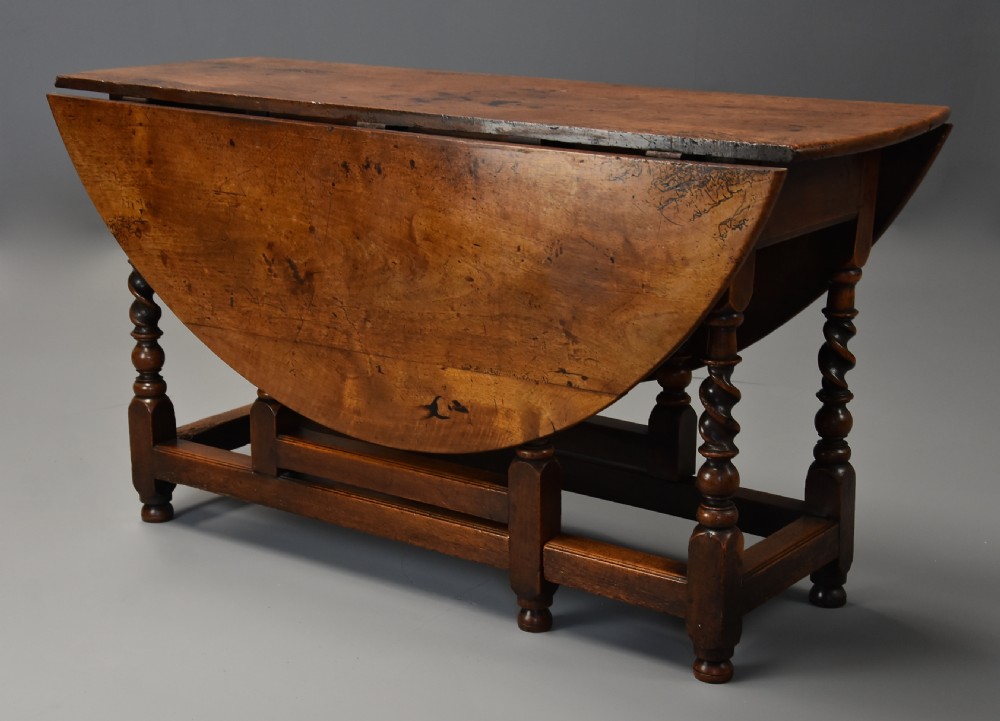 A 17th-century walnut gateleg table with extended oval drop leaves and double barley twist turned legs supported by stretchers. View VI
