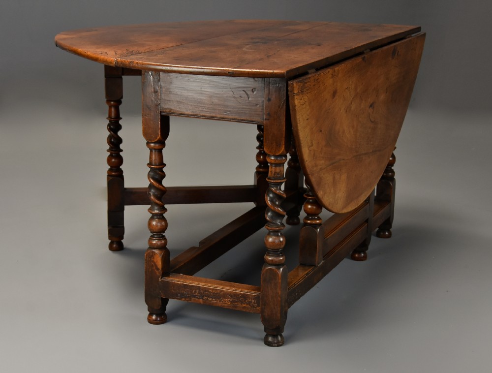 A 17th-century walnut gateleg table with extended oval drop leaves and double barley twist turned legs supported by stretchers. View IX